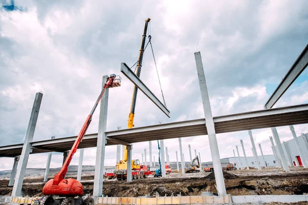 Tunga industriella kranen fungerar på byggarbetsplats, bygga konkreta hall med prefabricerade balkar — Stockfoto