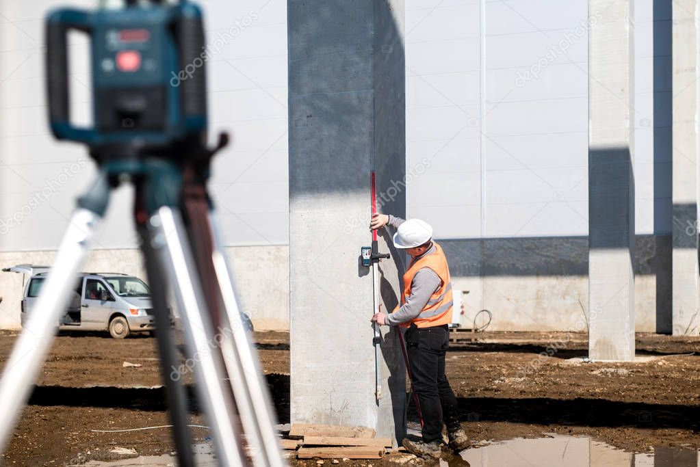 Industrial surveyor on construction site, working with thodolite, gps system and level machine 