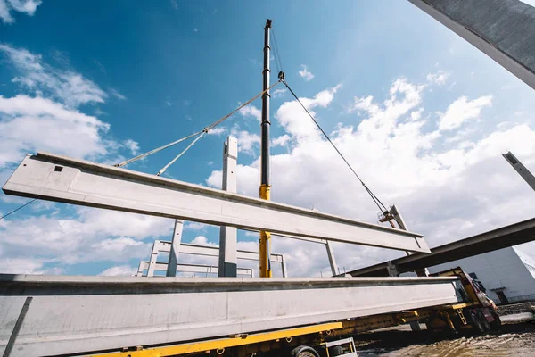 Industrial heavy duty crane lifting precast cement beams and pillars on construction site — Stock Photo, Image