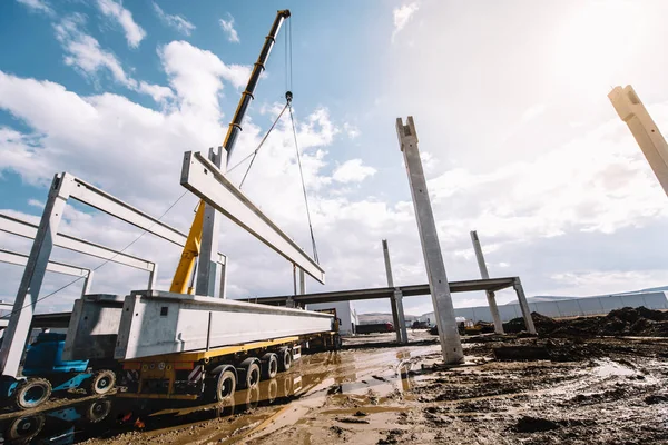 Pijlers van industriële bouwplaats van geprefabriceerde hal met cement en beton balken met bewegende kraan werken — Stockfoto