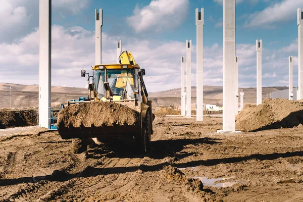 Industrial backhoe excavator and loader carrying earth and working on construction site — Stock Photo, Image