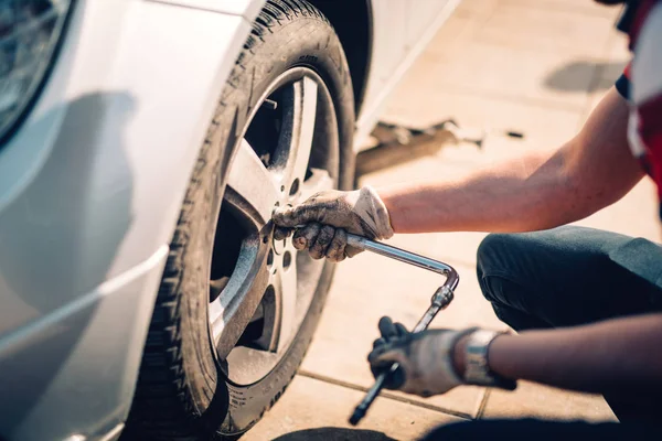 Reifenpflege, beschädigte Autoreifen oder der Wechsel von Saisonreifen mit dem Schraubenschlüssel. einen platten Autoreifen auf der Seitenstraße wechseln — Stockfoto