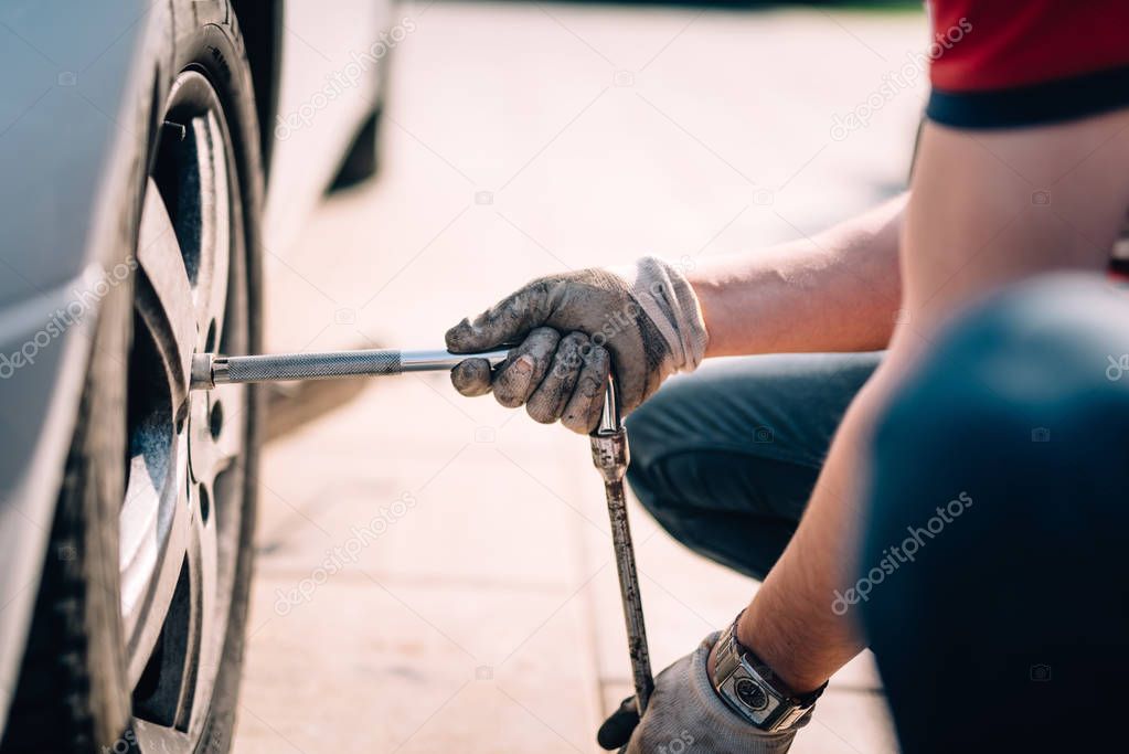 Details of mechanic changing tires, working in workshop and making repairs on automobiles