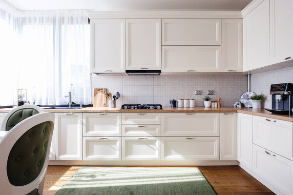 Дизайн интерьера кухни с деревянной мебелью, белыми деталями и паркетными полами
