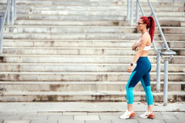 Spor kıyafetleriyle dışarıda egzersiz yapan çekici bir kadın. Kardiyo eğitimi sırasında dinlenen ve koşan kadın portresi