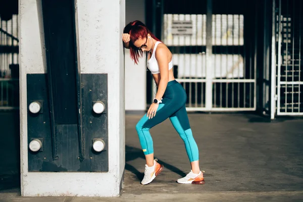 Mujer atractiva que usa ropa deportiva escuchando música mientras se estira y hace ejercicio —  Fotos de Stock