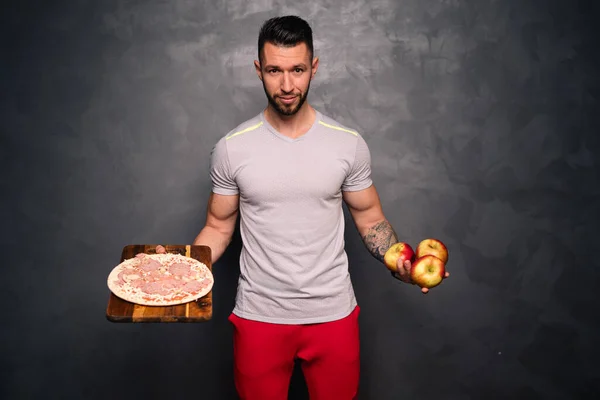 Healthy habits concept, healthy lifestyle concept with man wearing a shirt and holding a pizza and apples