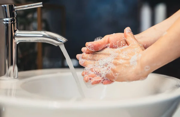 白人の若い女性は自宅のバスルームで石鹸と消毒剤で手を慎重に洗う — ストック写真