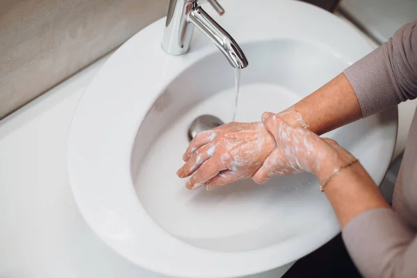 高齢の女性は慎重にバスルームで石鹸と消毒剤で手を洗う トップビュー衛生の詳細手と体の消毒 — ストック写真