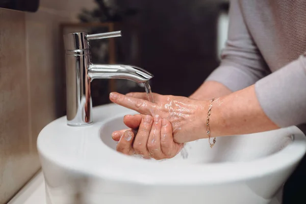 世界的なコロナウイルスのパンデミックの間に自宅で石鹸と消毒剤で手を慎重に洗う女性の閉鎖 — ストック写真