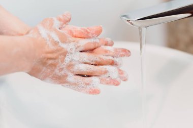 Musluk suyunun altındaki sabunla ellerin detaylarını kapat