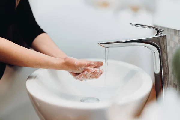 美しい女性は慎重にホームバスルームで石鹸と消毒剤で手を洗う — ストック写真