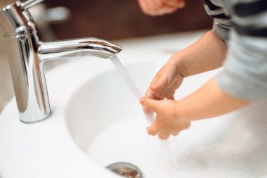 Hijyen ve el dezenfeksiyonu. Kafkasyalı bir adam küçük erkek çocukların ellerini yıkıyor, Kafkasyalıların evde bakım konsepti