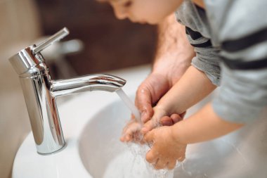 Çocuk ve baba ellerini yıkıyor, kovid hastalığını önlüyor. Beyaz ırkın hijyen detayları.