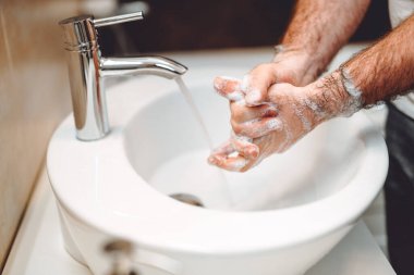 Coronavirus önleme konsepti - beyaz adam ellerini sabun ve musluk suyuyla yıkıyor