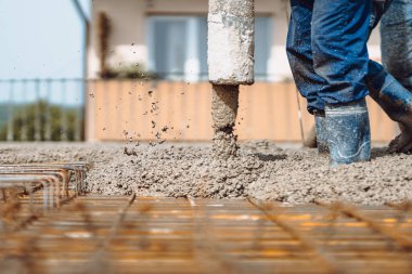 Otomatik boru pompasıyla beton döken işçiler. İnşaat alanının ayrıntıları ve işçilerin iş kıyafetlerinin ayrıntıları