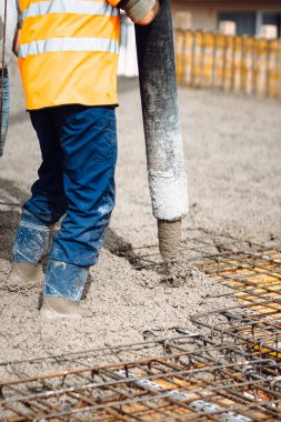 İnşaatçılar, beton pompayla beton döken beyaz işçiler. İnşaat alanının ayrıntıları