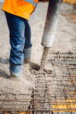 Çimento pompası ve beton döken güvenlik ekipmanı kullanan işçiler