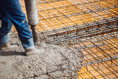 İnşaat işçisi pompa tübü ile çimento ya da beton döküyor. Güçlendirilmiş çelik çubuklar ve çubuklar