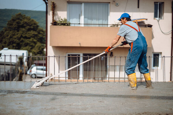 industrial workers pouring cement with manual pump tube, leveling concrete and finishing slab