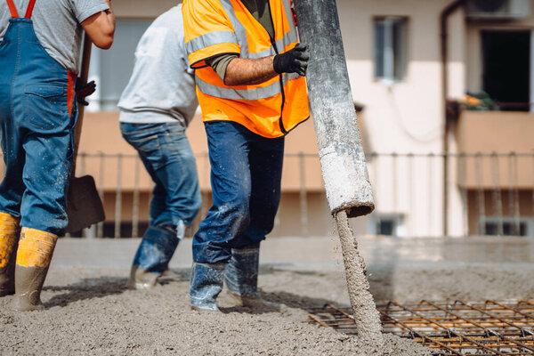 Construction details - worker laying and pouring cement or concrete with automatic pum
