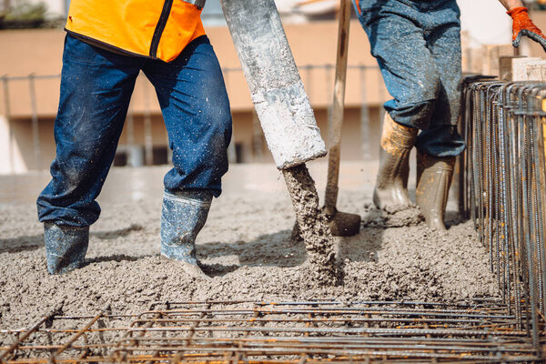 construction site details - building concrete slabs at house construction and pouring cement on reinforcement bars