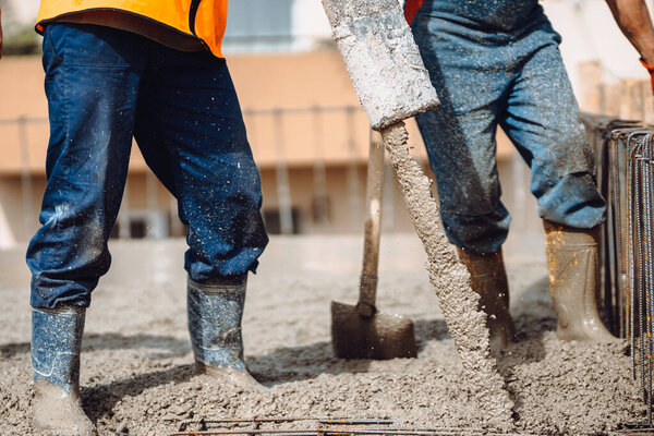 construction site details - building concrete slabs at house construction and pouring cement on reinforcement bars