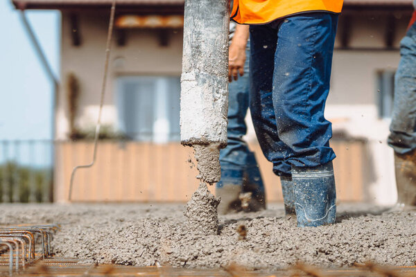 worker pouring concrete with automatic pump. Details of construction site and close up details of worker workwear