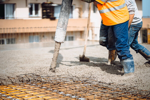 caucasian workers pouring concrete with concrete pump. Details of construction site and close up details of workers