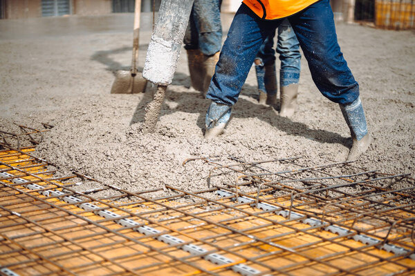 caucasian workers pouring concrete with concrete pump. Details of construction site and close up details of worker workwear