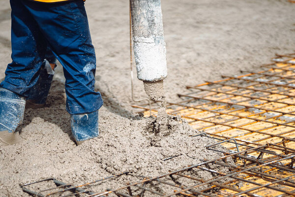 Construction worker working on building a house. Worker and cement pump
