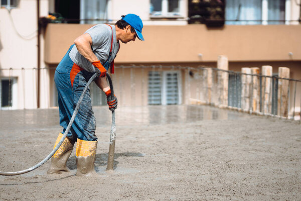 Worker using vibrator on construction site. Vibrating concrete on site
