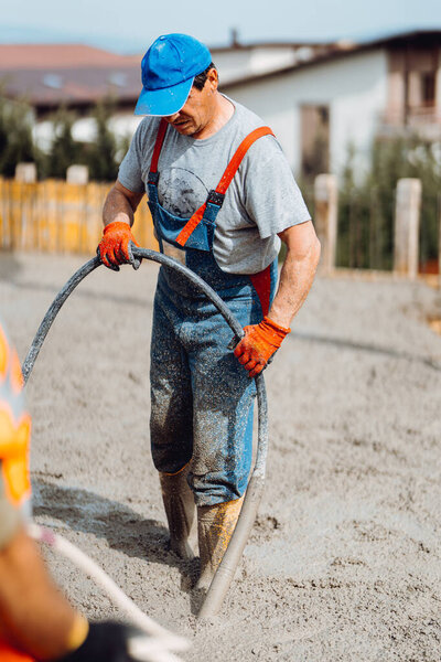 Construction worker working on building a house. Worker and concrete vibrator 
