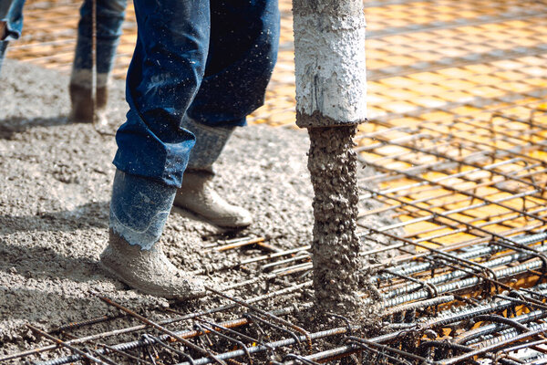 Construction worker pouring concrete, directing the pump tube pipe
