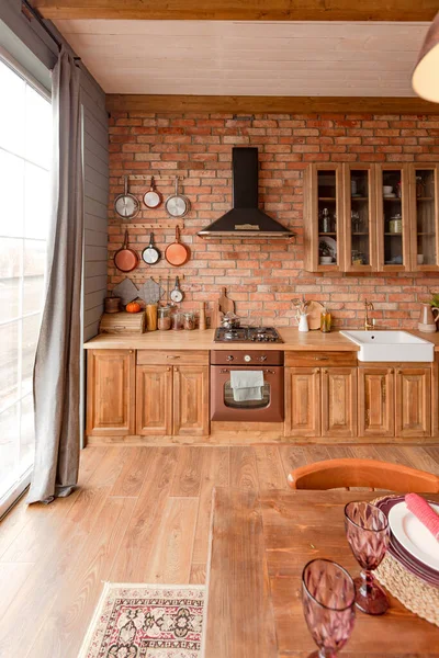 Interior of a country house in a wooden design, spacious living room with kitchen area and large windows, bedroom on the second floor