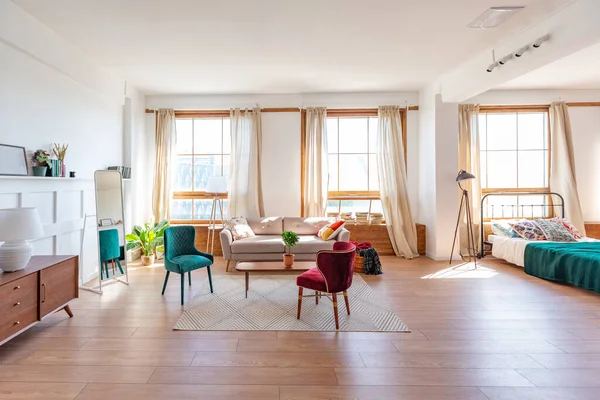 Vintage studio apartment interior in light colors in old style, large windows with living room area and bedroom area, direct sunlight inside