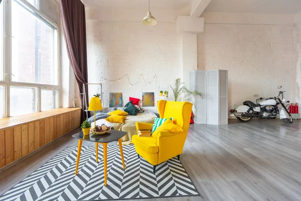 Trendy fashion luxury interior design in Scandinavian style of large spacious studio apartment with bright yellow furniture and decorated with new year tree.