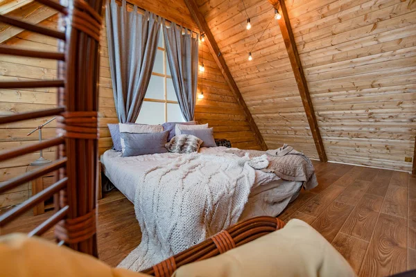 Interior of a country house in a wooden design, spacious bedroom on the second floor