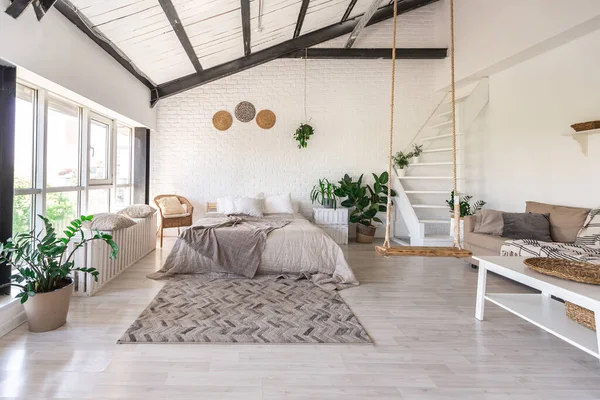 Luxury bedroom design in a rustic cottage in a minimalist style. white walls, panoramic windows, wooden elements of decoration on the ceiling, rope swings in the middle of a spacious room.