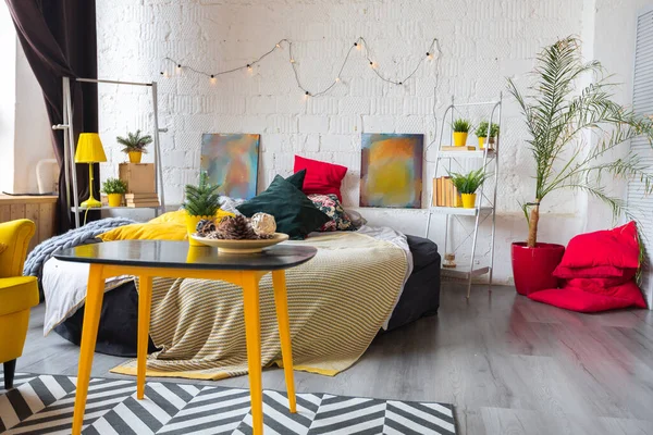 Trendy fashion luxury interior design in Scandinavian style of large spacious studio apartment with bright yellow furniture and decorated with new year tree.