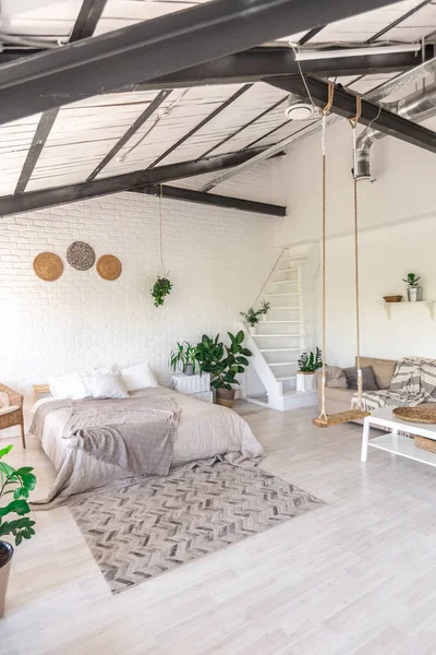 Luxury bedroom design in a rustic cottage in a minimalist style. white walls, panoramic windows, wooden elements of decoration on the ceiling, rope swings in the middle of a spacious room.