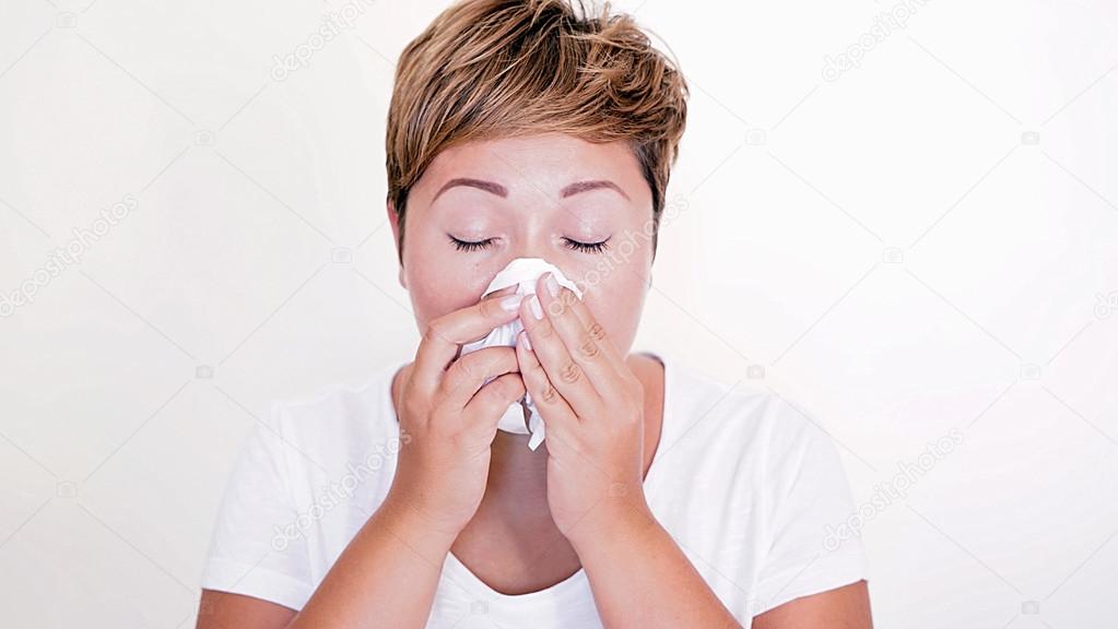 Short haired woman blowing her nose on the white background
