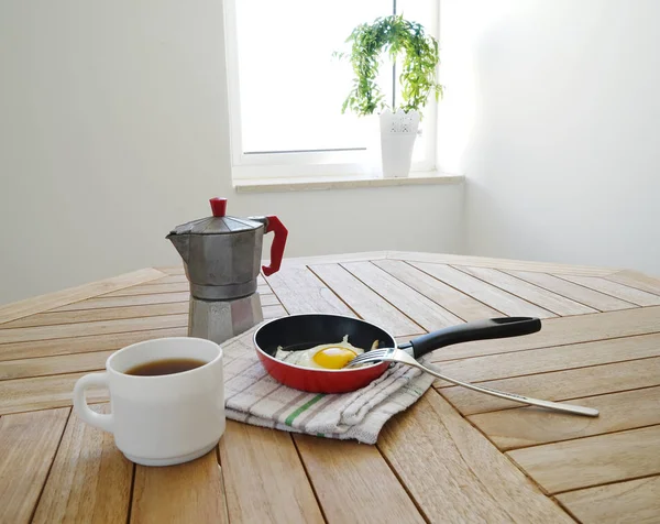Жареные яйца с кофейником на столе — стоковое фото