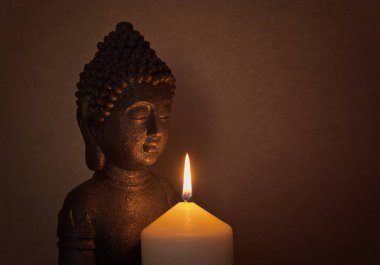 Bir mum ışığında kutsal bir Buda heykeli 