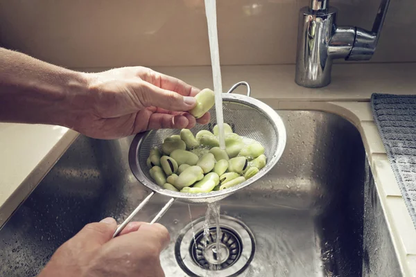 Las manos de los hombres se lavan en un tamiz frijoles verdes frescos — Foto de Stock