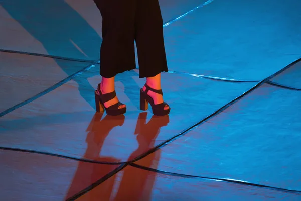 Women's legs in high heels on stage in the neon spotlight — Stock Photo, Image