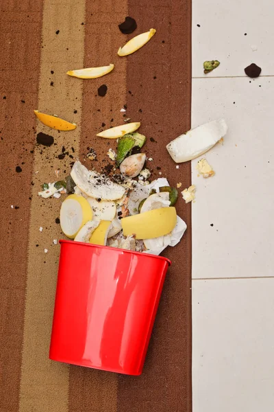 Röd plastpapperskorgen på golvet med utspritt organiskt avfall — Stockfoto