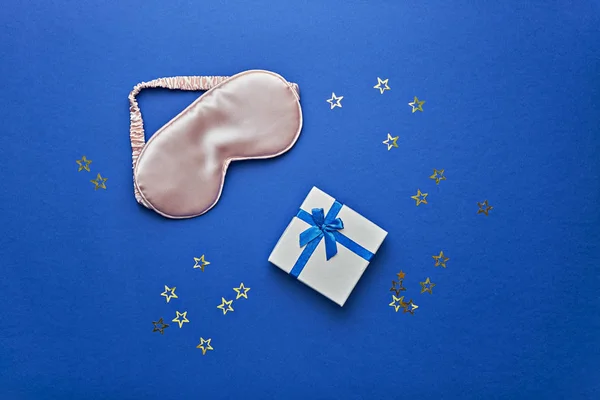 Sleeping mask ang gift box on blue background, flat lay — Stock Photo, Image