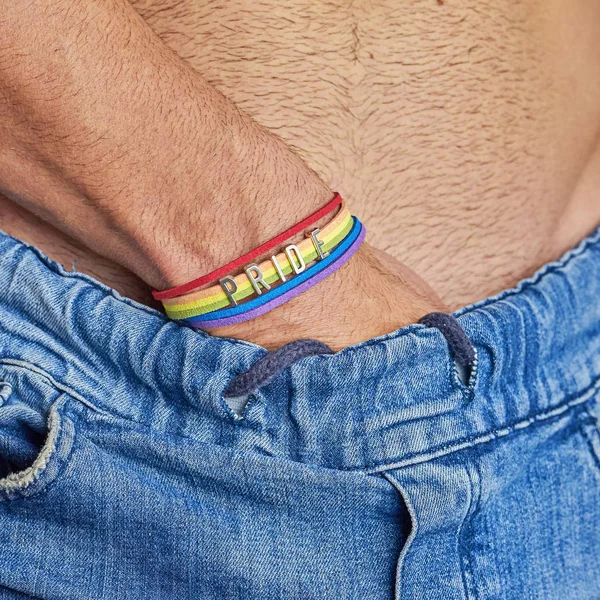Mano masculina con brazalete de arco iris y texto orgullo en cinturón jeans —  Fotos de Stock