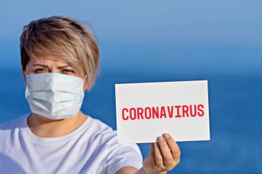Cerrahi maskeli kadın, Coronavirus 2019 metni ile boş duruyor.